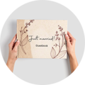 Hand houdt een liefdevol ontworpen gastenboek met de titel 'Just married!'