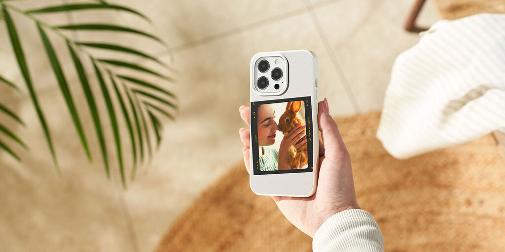 Een hand houdt een smartphone met foto's van een mooi moment. Planten en een tapijt op de achtergrond.