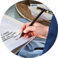 Een hand schrijft met een pen op een papier, omringd door schrijfwaren.