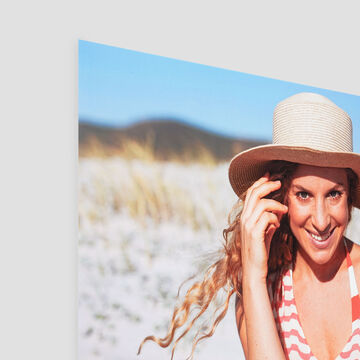 Een persoon met zonnehoed en gestreepte top, ontspannen op het strand in de zon