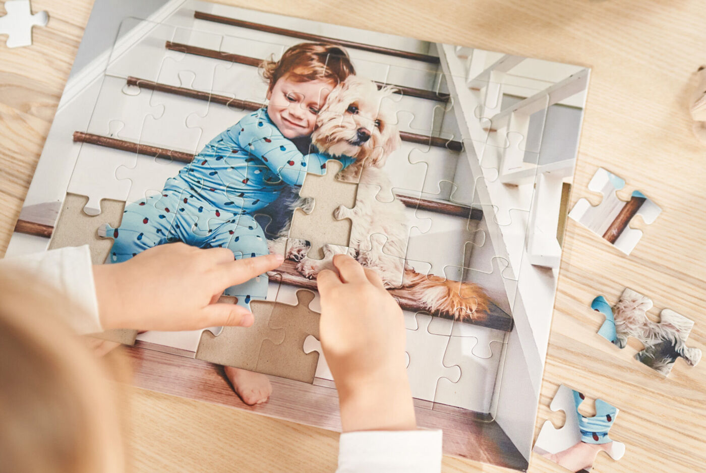 Een kind plaatst een puzzelstuk op een puzzel met een hond.