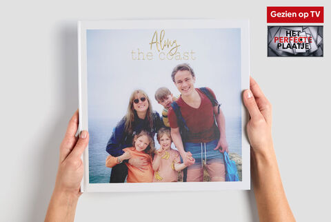 Een gezin houdt een CEWE FOTOBUCH met strandthema's.