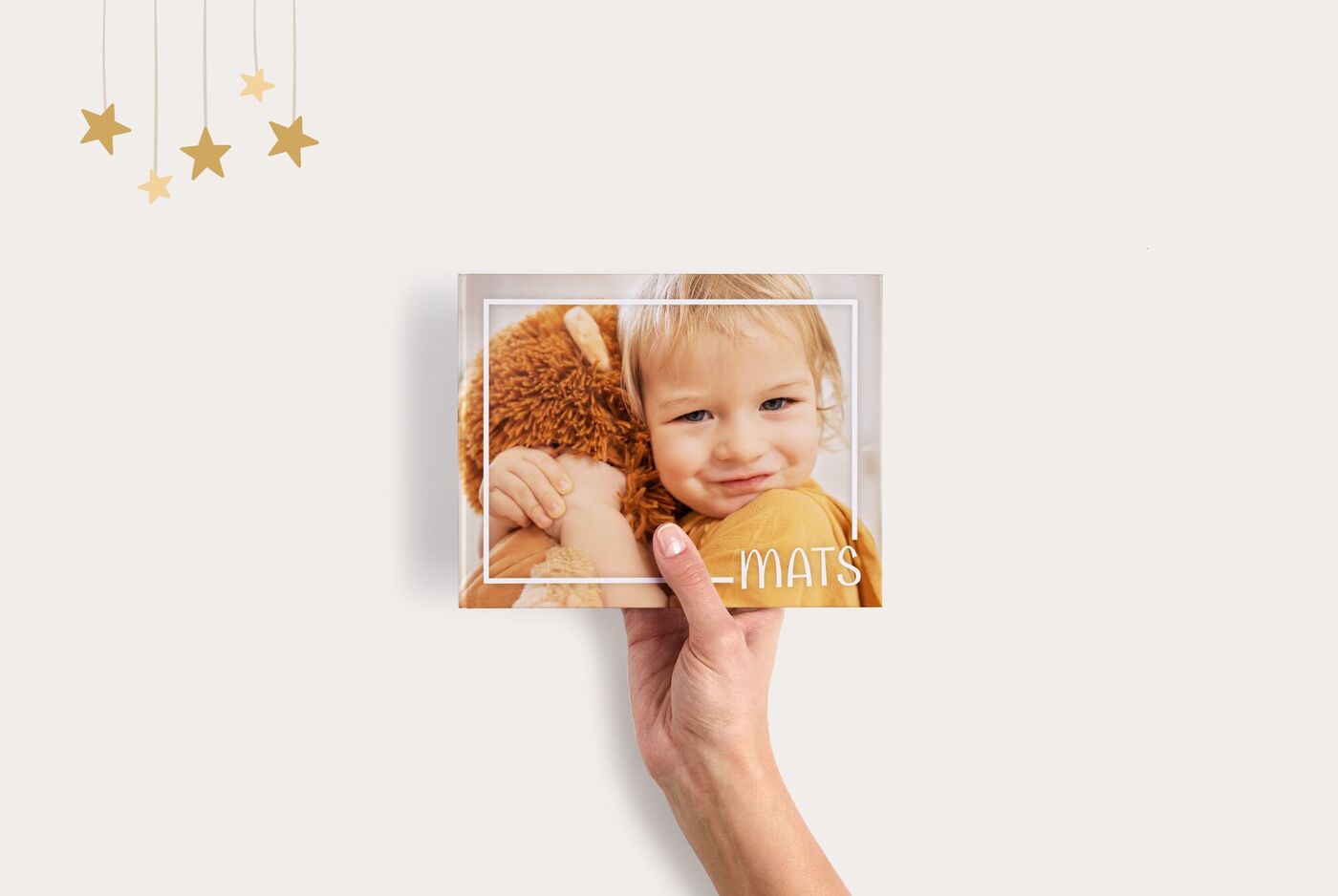 Een hand houdt een CEWE Fotoboek vast met de titel "Mats".
